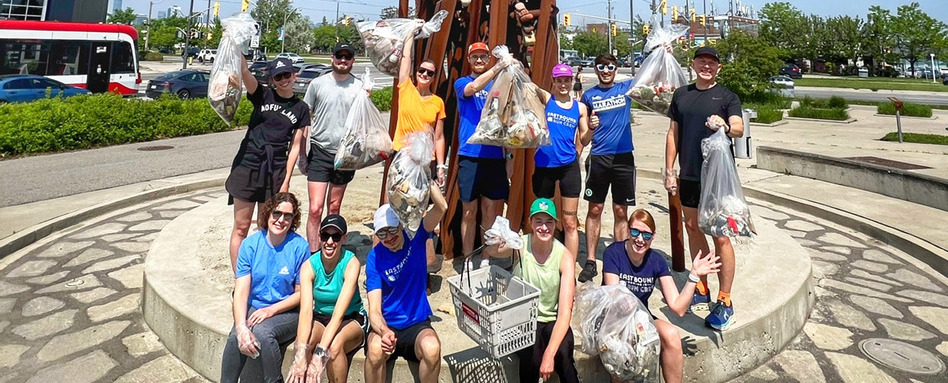 people smiling holding up trash