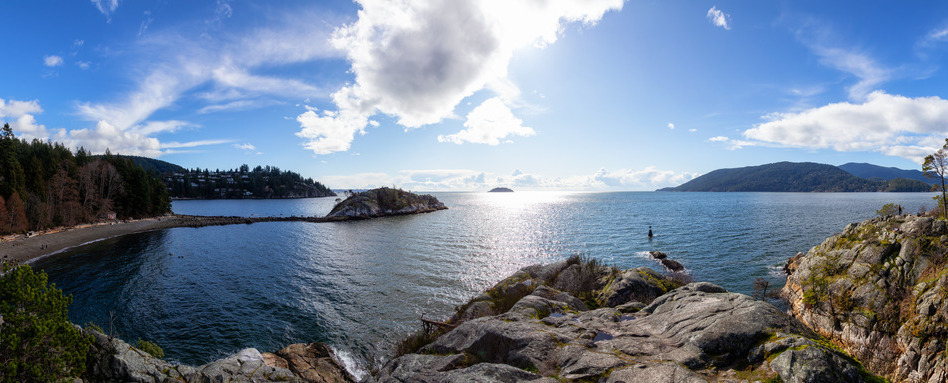 panoramic sea wall with mountains and jagged shore line on a sunny day