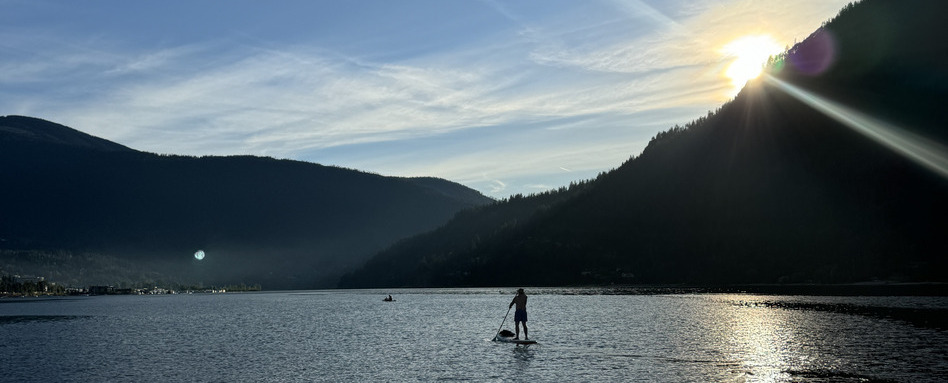 person paddleboarding on water with mountains being