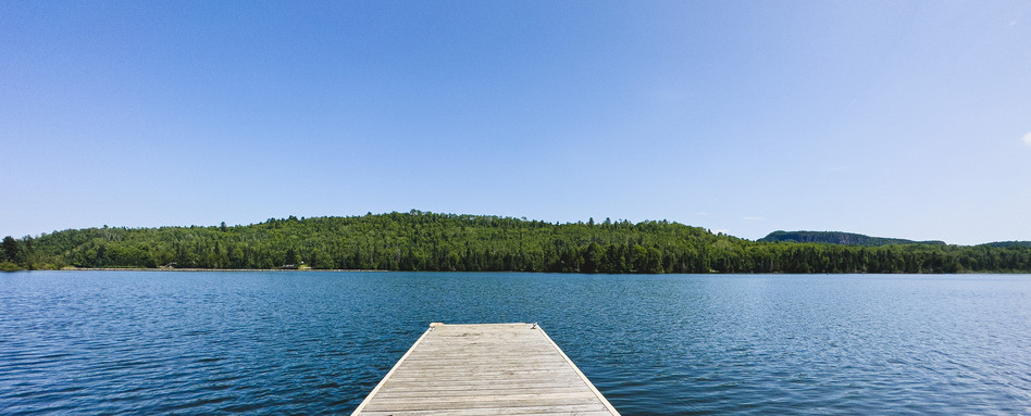 Wooden dock extending into the calm blue waters of the Nipigon River along the Voyageur Trail in Ontario