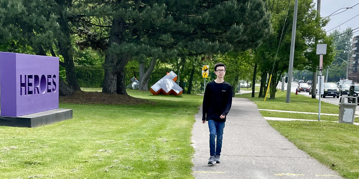 man walking down a paved sidewalk with forest behind