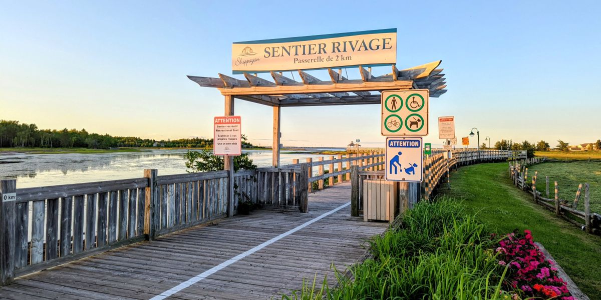 a sign reading 'sentier rivage' overlooking a body of water on a trail