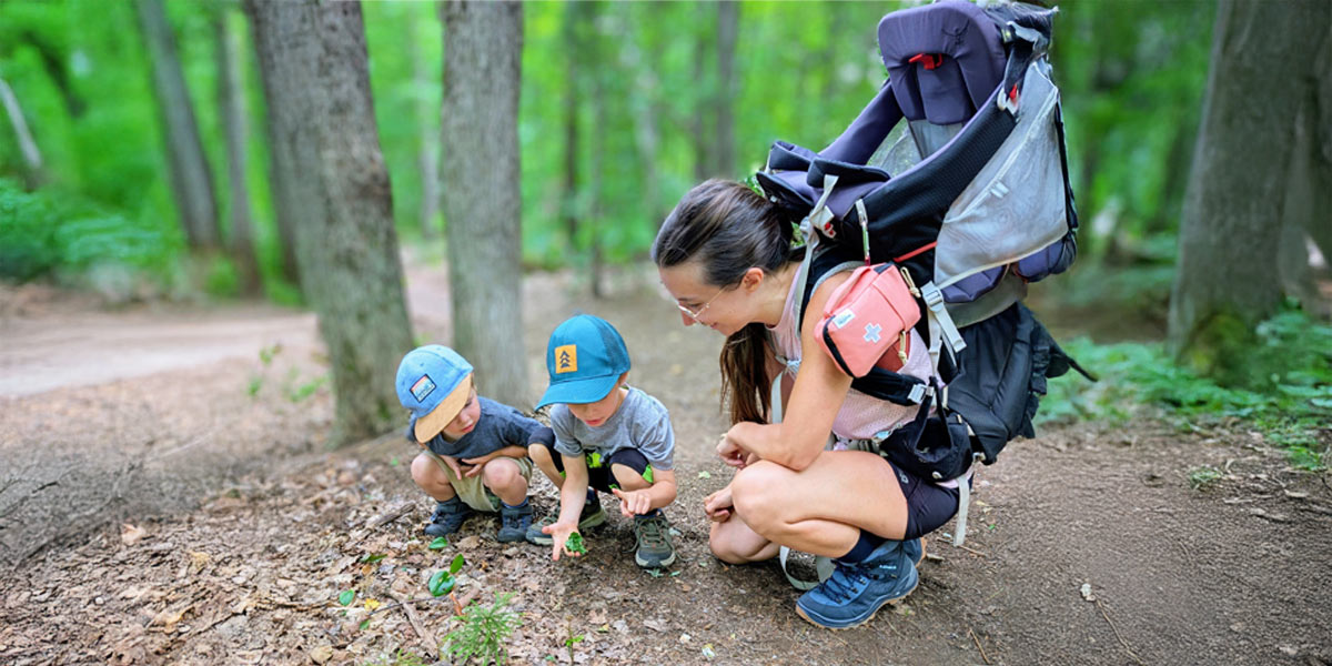 woman kneeling with two young children in a forest
