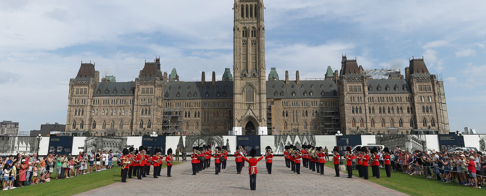 RCMP standing in uniform infront of canadian parliament building