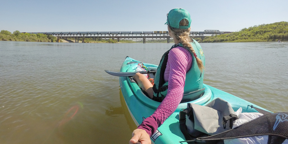 Woman paddling a kayak on a waterway.