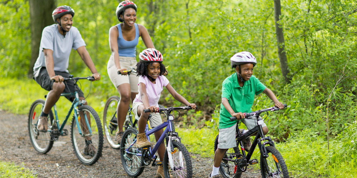 family smiling while riding bikes through the forest