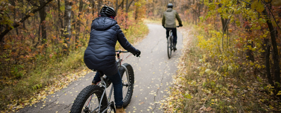 two people on bikes on a trail in the fall