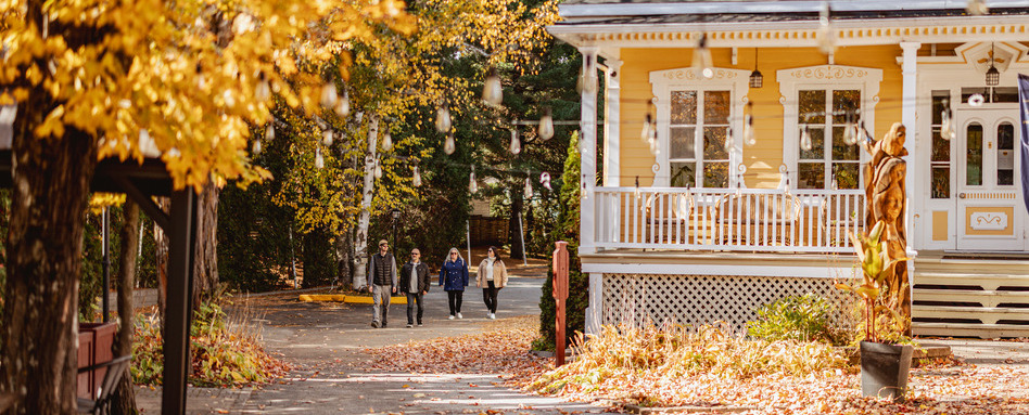 people walking through fall foliage with town buildings surrounding