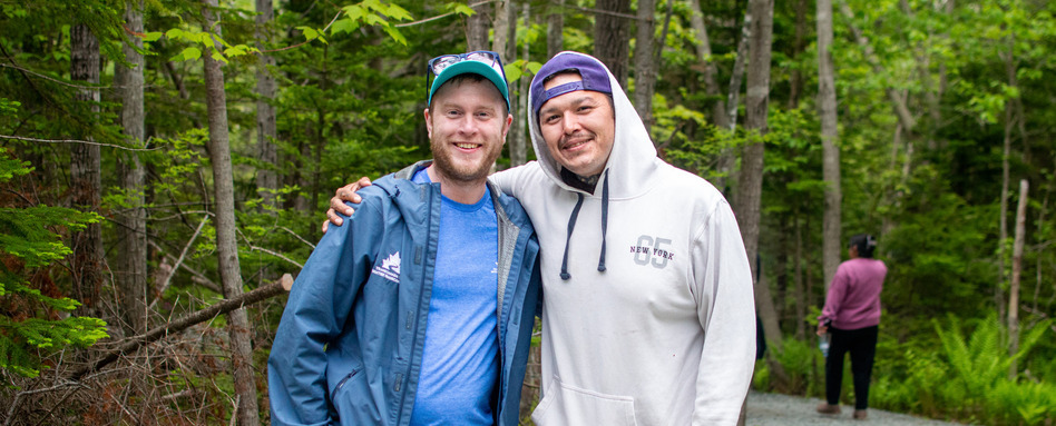 two men posing for a photo in a forest