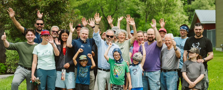 people waving at a camera posing for a photo in a field