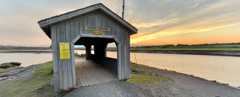 covered bridge over a body of water at sunset