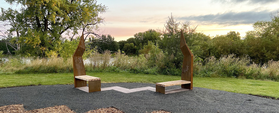 benches and are on a grassy surface with sunset in the background