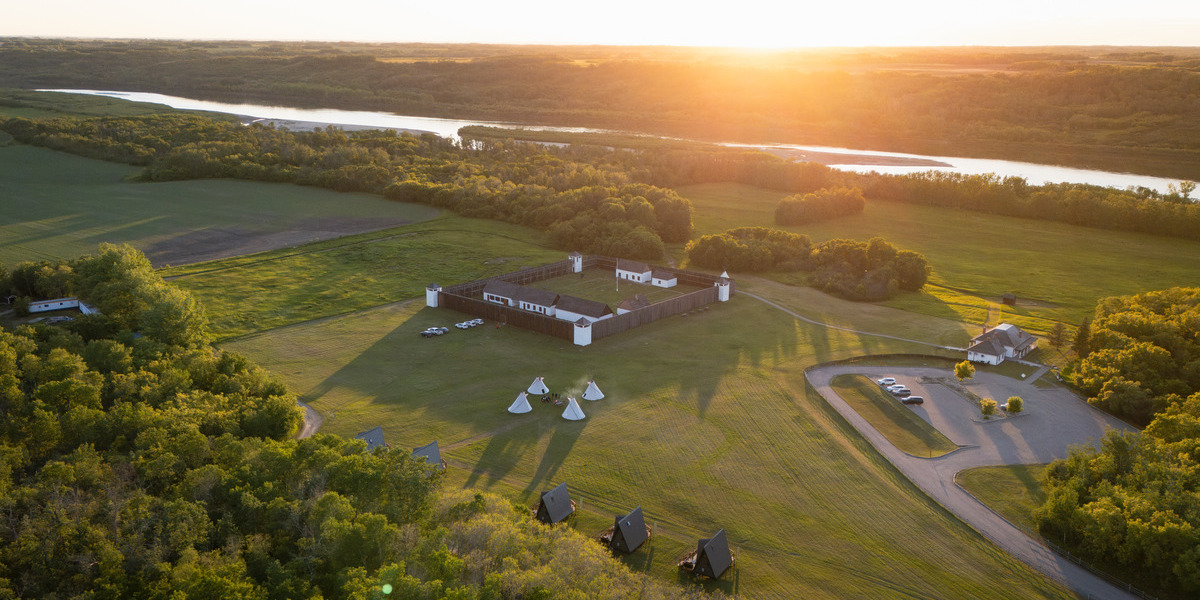 birdseye view of field with teepees and forest during sunset
