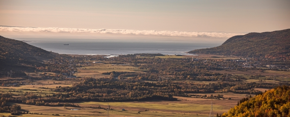 view out to rolling hills, forest and lake and blue sky