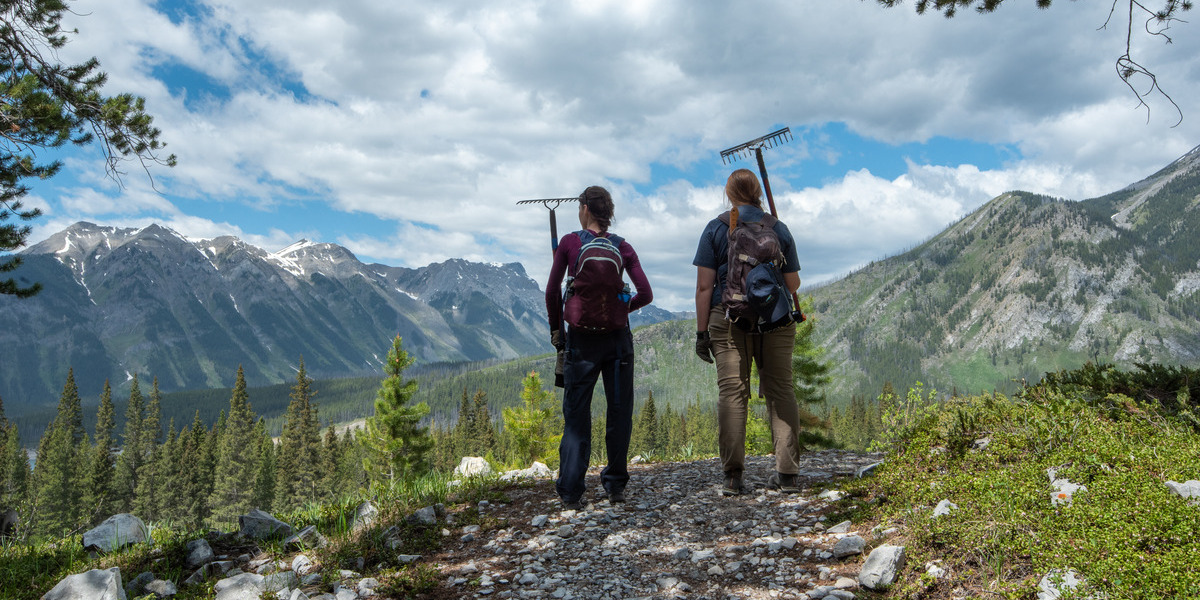 two people standing on a mountain in hiking gear on a sunny day