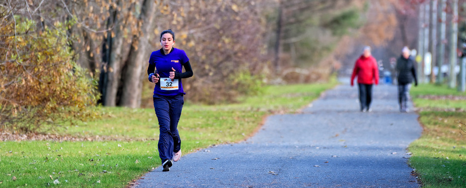 A woman running along a trail, dressed in blue with the number 32 on her shirt.