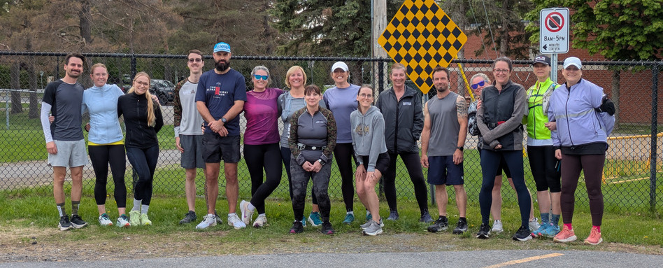 A group of people posing for a picture, standing on the side of the road, dressed in athletic clothing.