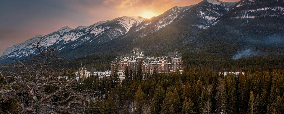 Spooky Stories_Fairmont Banff Springs_Photo by Lisa Bourgeault | Trans Canada Trail birdseye view of fairmont hotel with mountain and sunrise behind on snowy day