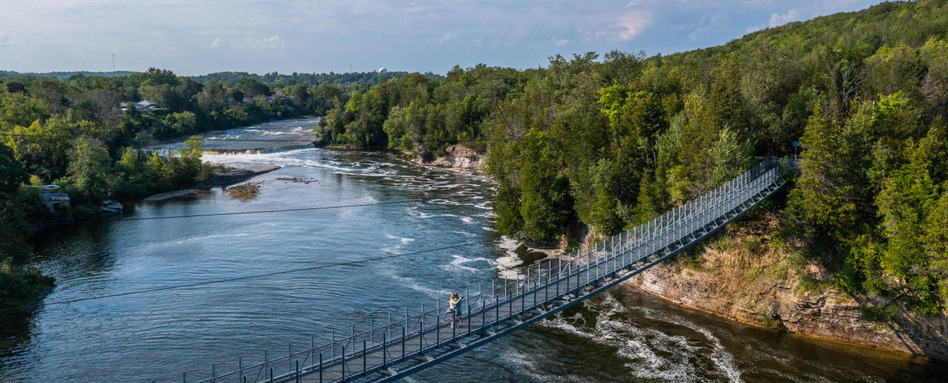 suspension bridge birdseye view over water and forest