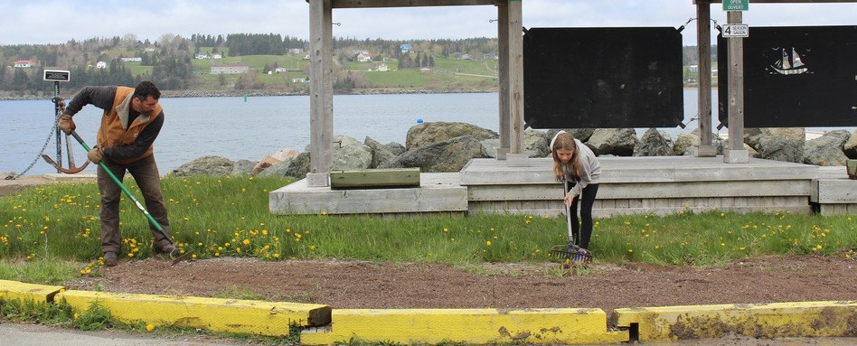 people cleaning up a trail section with water and homes in background