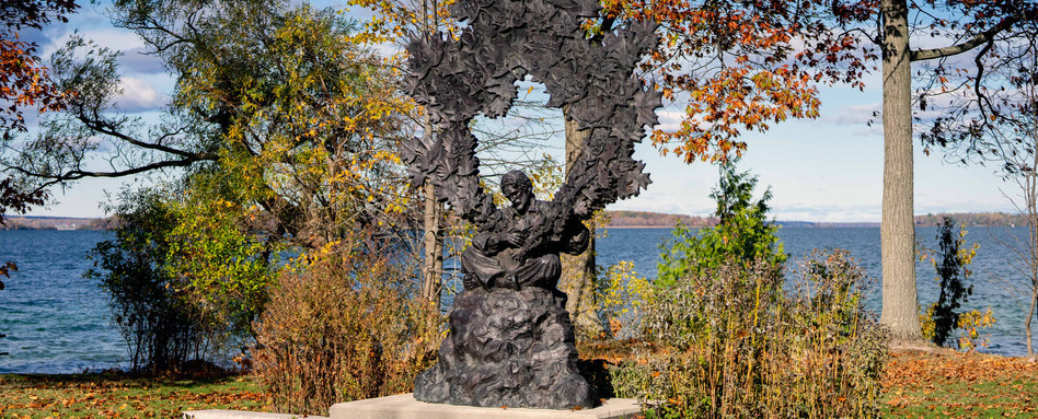 large statue with trees and water behind on a sunny day