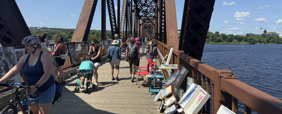 people walking on a bridge lined with art