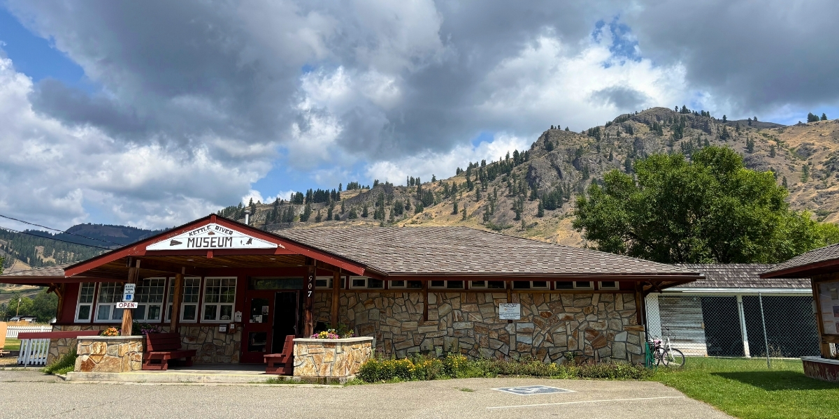 00Feature image option 2_BC_Midway KVR | Trans Canada Trail photo of large building in empty lot with mountain behind on a cloudy day
