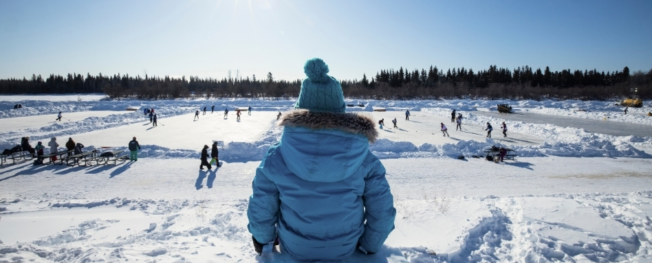 02Support image_NWT winter activities_Credit Paul Zizka and NWTT_dont use outside of NWT promotion | Trans Canada Trail person in winter gear overlooking a skating pond on a sunny day