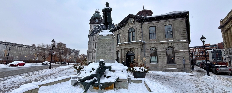 snowy historic buildings and statues on a cloudy day