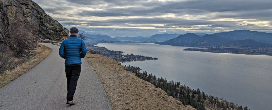 large body of water and mountains alongside runner on pathway