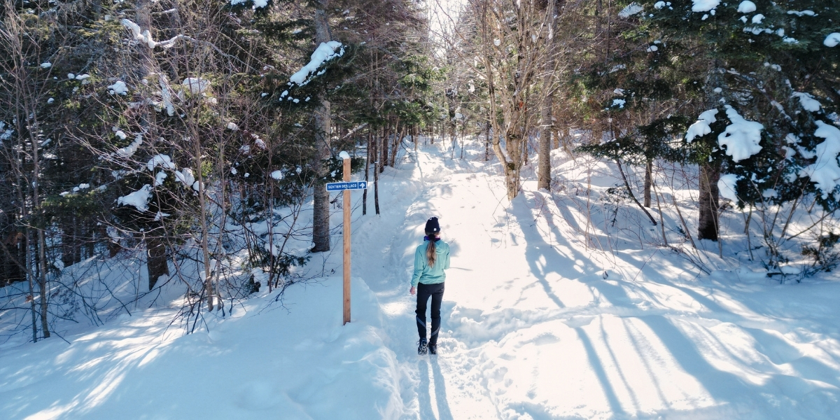 00Feature image_QC_Sentier des Caps_Web story_credit Au Québ | Trans Canada Trail woman walking on snowy trail on sunny day