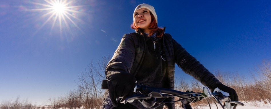 03SK_Pemiska_Support image_fat tire biking sun flare_Credit Pemiska Tourism | Trans Canada Trail A person looking up at the blue sky, holding onto bike handles