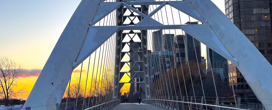 ON_Martin-Goodman-Trail_Rudderless-Travel-14_Web_StorySupport_Image_948x383 1 | Trans Canada Trail A metal bridge at sunset with city buildings in the background