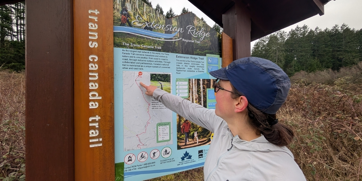 00Feature image_BC_Ali Becker Extension Ridge_credit Ali Becker | Trans Canada Trail person pointing at a large trail map in a meadow