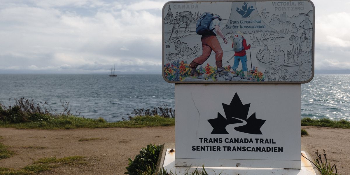 00Feature image_Victoria - Dallas Road - 10_credit Meg Pender | Trans Canada Trail signage on a trail of man and boy hiking with water behind
