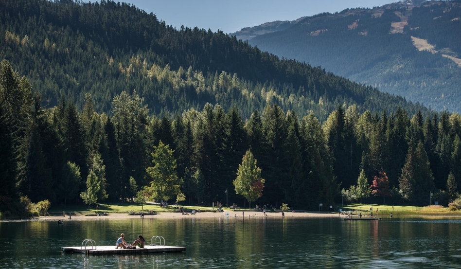 02Support image_Whistler Museum story_Lost Lake_credit Destination BC-Blake Jorgenson | Trans Canada Trail large dock with two people sitting overlooking a lake and rolling mountains