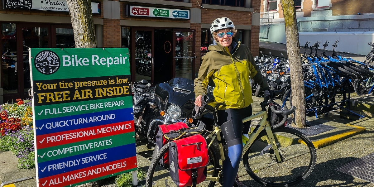00Feature image_Leigh McAdam bikepacking_credit Leigh McAdam | Trans Canada Trail woman in front of signage posing with bikes