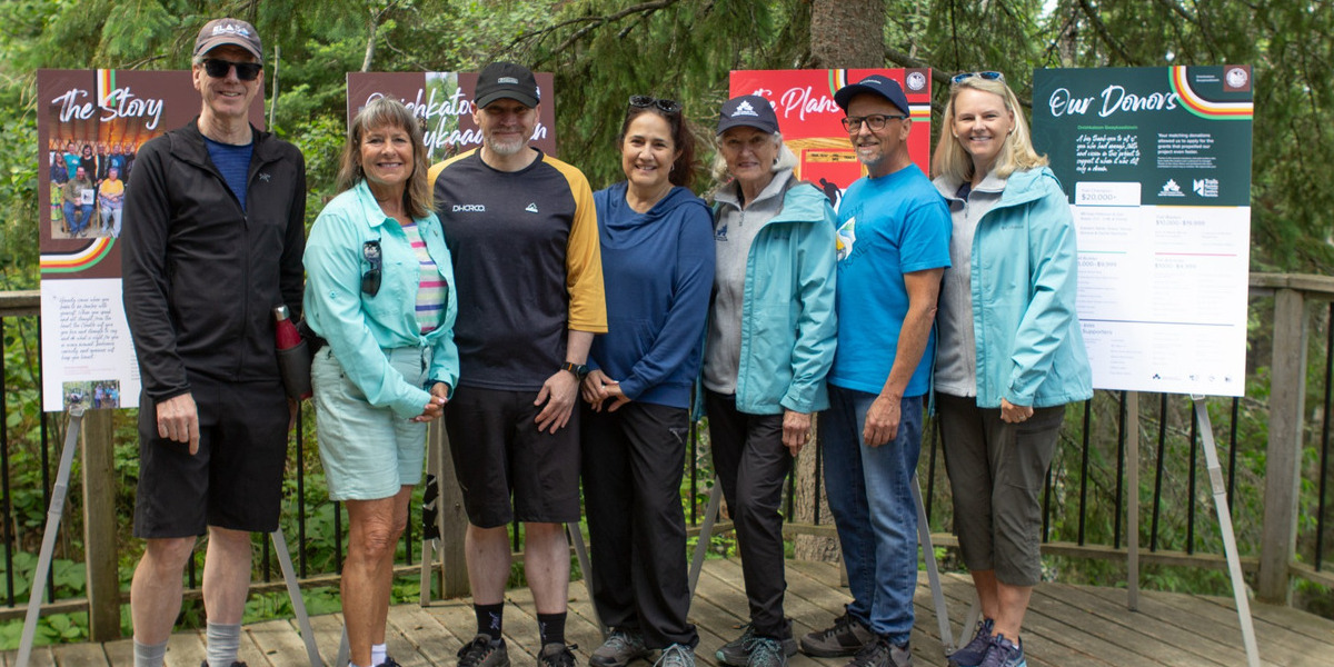 group of people posing infront of trail signage in forest