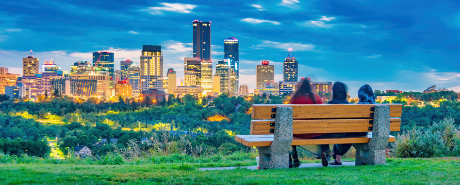 Edmonton Skyline Alberta Canada People relax on bench | Trans Canada Trail skyline view of two people sitting on a bench at dusk