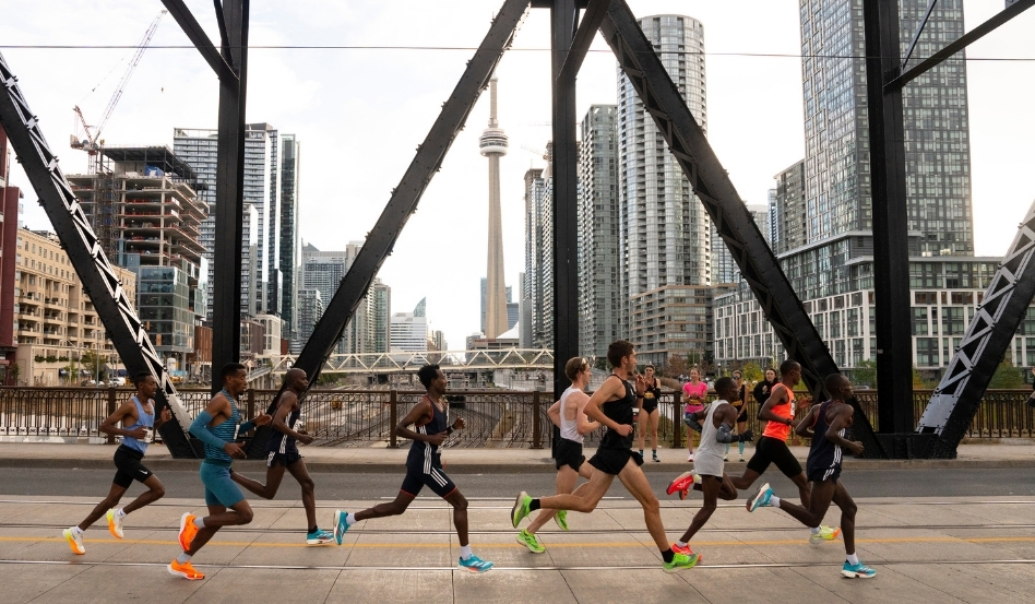 01Support image_Jen Cerullo profile_credit Canada Running Series | Trans Canada Trail people running as a group on a bridge with toronto skyline behind