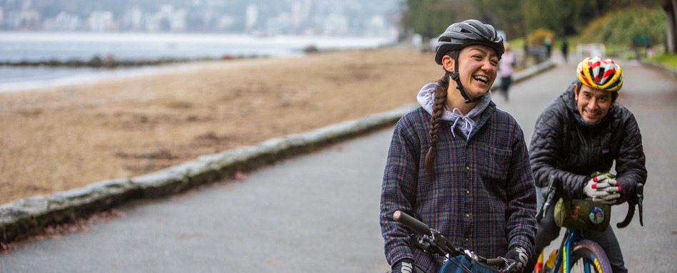 two people on bikes smiling on a seaside trail