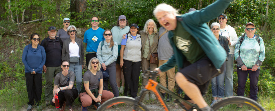 man races by on bicycle infront of group of people on a trail