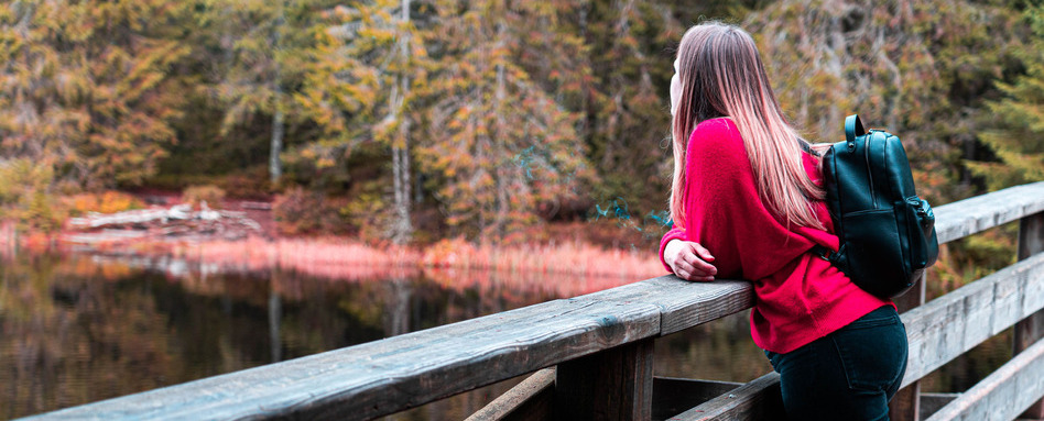 01Support image_Early Registration story | Trans Canada Trail woman standing on a bridge overlooking a lake and trees