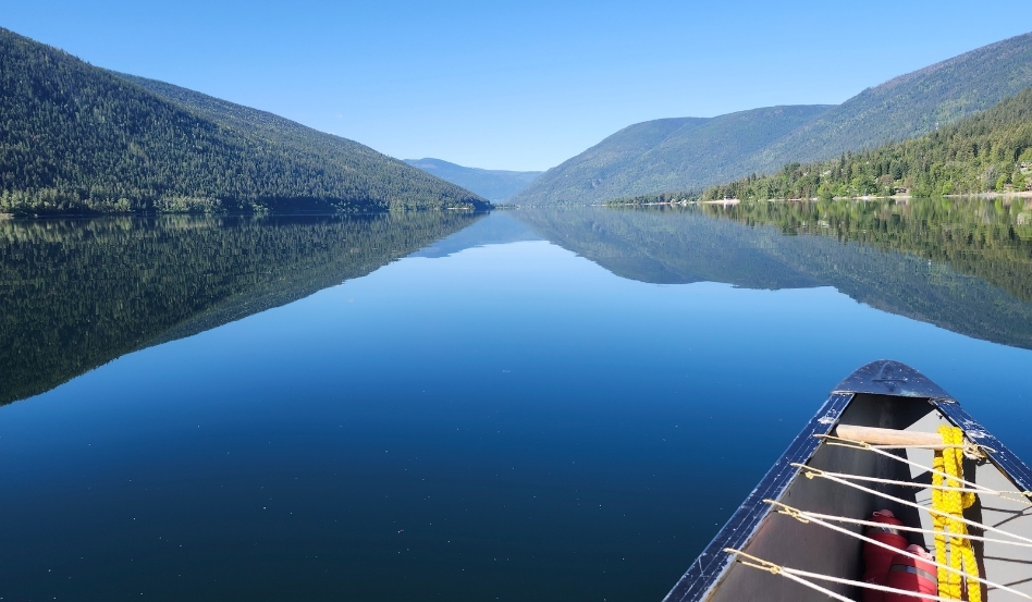 02Support image_Ali Becker West Arm Paddle Route_web story_credit Ali Becker | Trans Canada Trail canoe on large open water with mountains on a sunny day