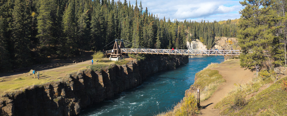 02Support image_GCH Northern Canada_Whitehorse_credit Bich-Anh Nguyen | Trans Canada Trail bridge over water rapids in forest on sunny day