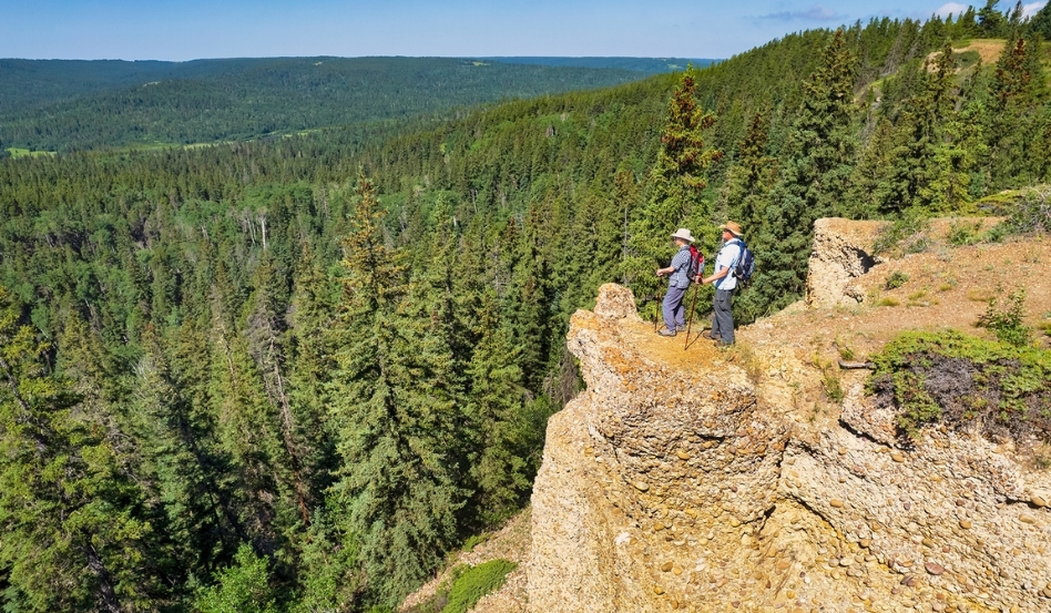 03Support image_SK_Cypress Hills Interprovincial Park_on cliff_credit Robin and Arlene Karpan | Trans Canada Trail Two people standing on a cliff facing to the left, overlooking a hilly forest