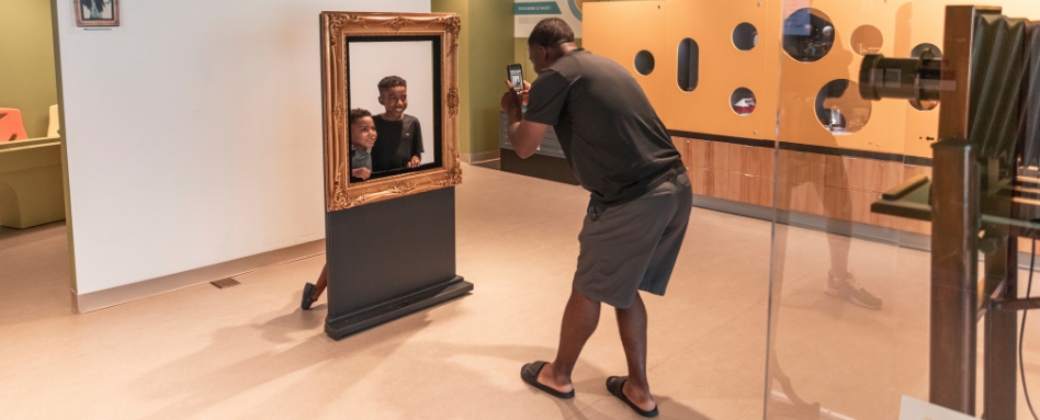 04Support image_TWEPI article_Chimzuk Museum_credit Tourism Windsor Essex Pelee Island | Trans Canada Trail man taking a photo of kids in a photo frame at museum