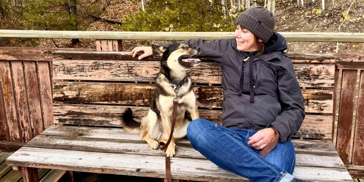 00Feature image_Mel Vogel GCH profile_photo credit Mel Vogel | Trans Canada Trail A woman and her dog sitting on a bench, looking at one another