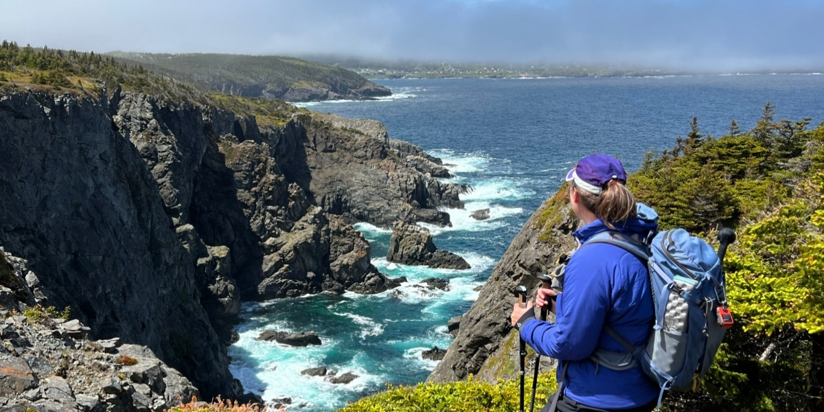 A person looking out over a rocky cliff with the ocean below