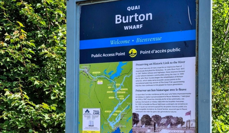 05Support image_Blue Trails NB_credit Cathy Donaldson_signage | Trans Canada Trail Signboard for Burton Wharf with Welcome message and river trail map, set against greenery.
